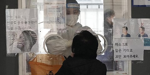 A medical worker in a booth takes a nasal swab sample from a woman at a makeshift testing site in Seoul, South Korea, Tuesday, March 15, 2022. (Photo | AP)