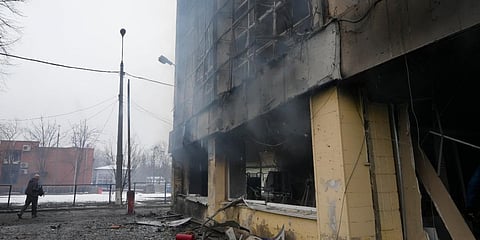 A journalist walks past a damaged building following shelling in Kyiv, Ukraine. (Photo| AP)