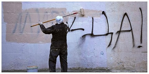 A worker paints over graffiti saying 'Yes to Peace!' on a wall of an apartment building in St. Petersburg, Russia, Friday, March 18, 2022. (Photo | AP)