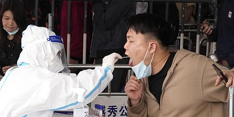 A worker takes a swab from a passenger for a COVID-19 test at the Guangzhou train station on Friday, March 25, 2022.(Photo | AP)