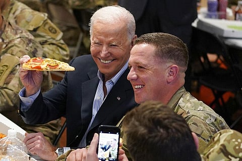 President Joe Biden holds a piece of pizza as he posed for a photo during a visit with members of the 82nd Airborne Division at the G2A Arena, Friday, March 25, 2022. (Photo | AP)