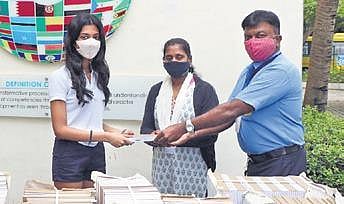 A 17-year-old student Diya (centre) distributes the re-purposed notebooks.  (Photo | EPS)
