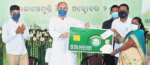 Chief Minister Naveen Patnaik handing over a smart card to a beneficiary. ( Photo | EPS)