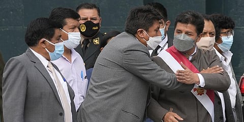 Peru's President Pedro Castillo, right, is embraced by one of his party´s lawmakers as he leaves Congress where lawmakers voted to proceed with impeachment proceedings against him.(Photo | AP)