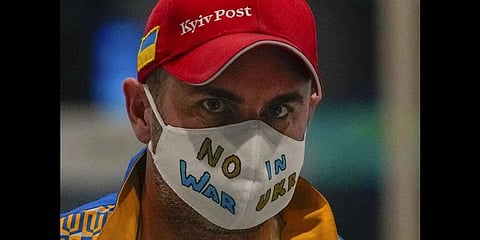 A Ukrainian journalist wearing a face mask bearing the words 'No War in Ukraine' walks through the Main Media Center ahead of the 2022 Winter Paralympics in Beijing, China