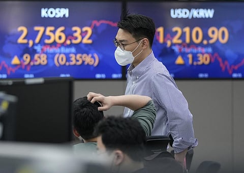 A currency trader watches monitors in front of screens showing the Korea Composite Stock Price Index (KOSPI) and the foreign exchange rate between U.S. dollar and South Korean won. (Photo | AP)
