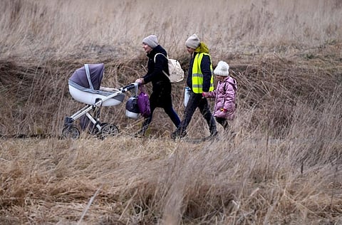 A woman wheels a baby carriage, as she walks with others fleeing Ukraine, at the border crossing in Medyka, Poland. (Photo | AP)