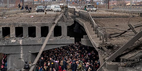 Ukrainians crowd under a destroyed bridge as they try to flee crossing the Irpin river in the outskirts of Kyiv, Ukraine, Saturday, March 5, 2022. (Photo | AP)