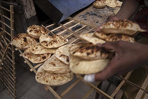 A worker collects Egyptian traditional 'baladi' flatbread, at a bakery in Cairo. The Russian invasion of Ukraine threaten the food supply and livelihoods of people in Europe, Africa & Asia. (AP Photo)
