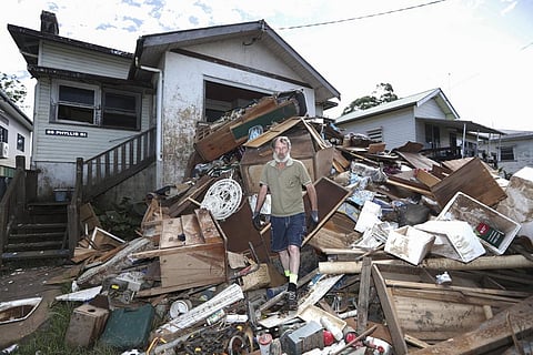 Resident Ken Bridge stands on a pile of his flood-damaged furniture outside his home in Lismore, Australia. (Photo | AP)