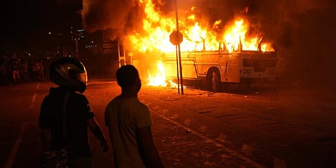 Sri Lankans watch after setting a bus on fire during a protest outside Sri Lanka President Gotabaya Rajapaksa's private residence on the outskirts of Colombo, Sri Lanka. (Photo | AP)