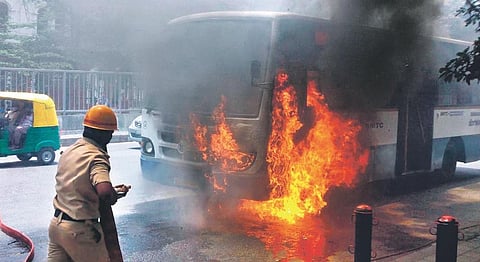 A fire personnel tries to douse the fire after a BMTC bus caught fire at KR Circle in Bengaluru on Saturday. All 35 passengers aboard the bus escaped unhurt | Express