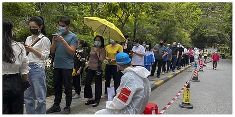 Workers in protective gear watch over residents line up for the COVID-19 test at a residential block, Monday, April 11, 2022, in Guangzhou in south China's Guangdong province. (Photo | AP)