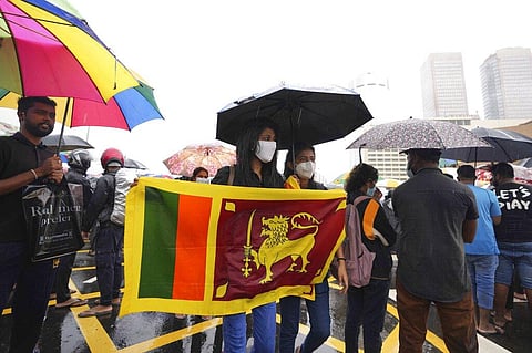 Sri Lankans demanding president Gotabaya Rajapaksa resign over the debt-ridden country’s worst economic crisis protest in the rain outside the president's office in Colombo. (Photo | AP)