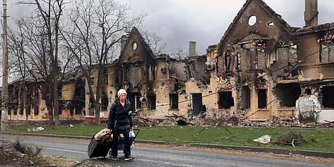 A woman pulls her bags past houses damaged during fighting in eastern Mariupol, Ukraine. (Photo| AP)