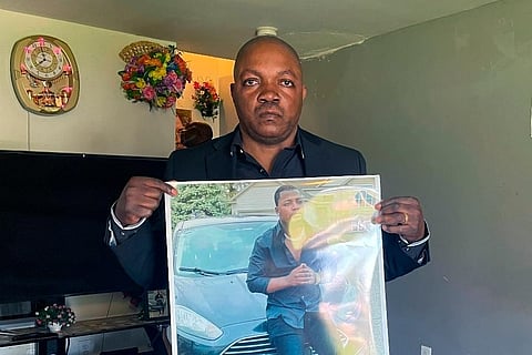 Peter Lyoya holds up a picture of his son Patrick Lyoya, 26, in his home in Lansing. ( Photo | AP)