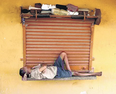 A worker takes a nap outside a closed shop in Bhubaneswar  | Express
