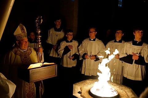 Archbishop Bernard Hebda, left, smiles before blessing the fire and the Paschal candle at the Cathedral of St. Paul . ( Photo | AP)