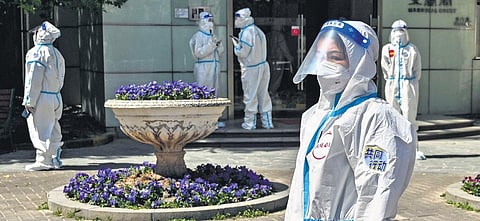 Workers and volunteers look on in a compound where residents are tested for the Covid-19 pandemic in Shanghai.(File Photo | AFP)