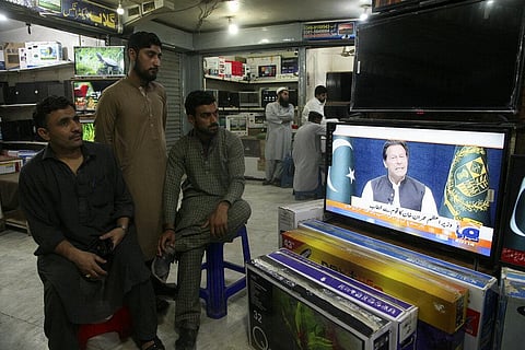 People watches news channels broadcast a live address to the nation by Pakistan's Prime Minister Imran Khan at a market, in Peshawar, Pakistan. (Photo | AP)