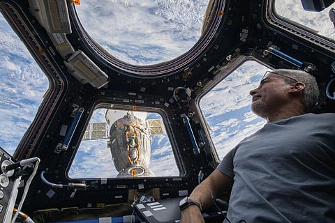 In this photo provided by NASA, U.S. astronaut and Expedition 66 Flight Engineer Mark Vande Hei peers at the Earth below from inside the seven-windowed cupola. (Photo | AP)