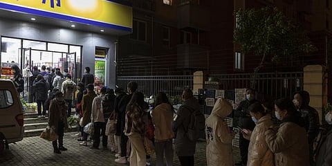 Residents wearing face masks to help protect from the coronavirus line up outside a supermarket at night to buy groceries in Shanghai, China. (Photo | AP)