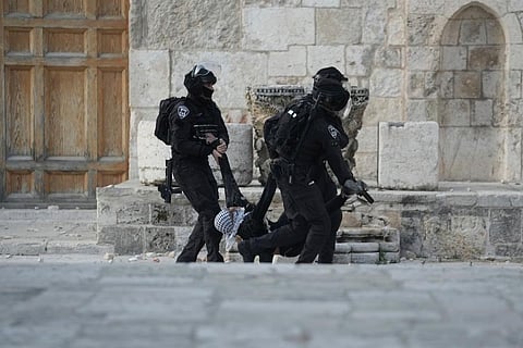 Israeli police carry a Palestinian protester during clashes at the Al Aqsa Mosque compound in Jerusalem's Old City. ( Photo | AP)