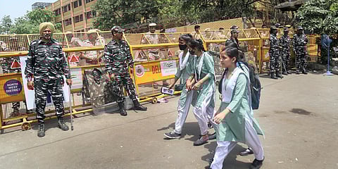 Security forces personnel stand guard as girls walk to school in the violence-hit Jahangirpuri area, in New Delhi. (Photo| PTI)
