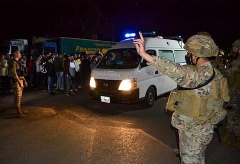 Lebanese soldiers and onlookers stand at the entrance of the port of Tripoli, as an ambulace carrying survivors. (Photo | AFP)