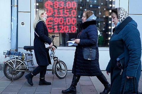 People walk past a currency exchange office screen displaying the exchange rates of U.S. Dollar and Euro to Russian Rubles in Moscow's downtown, Russia. ( Photo | AP)