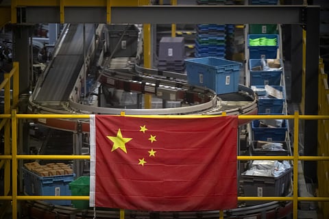 In this Nov. 11, 2020, file photo a Chinese flag hangs near an automated parcel handling line at a warehouse for an online retailer in Beijing. (File photo | AP)