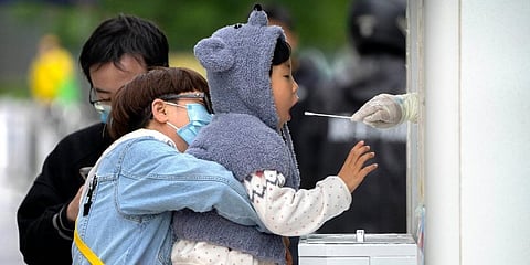 A child receives a throat swab for a COVID-19 test at a testing site in Beijing. (Photo | AP)