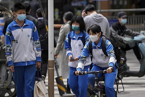 Secondary students wearing face masks wonder along a street in Beijing. (Photo | AP)