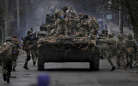 Ukrainian servicemen climb on a fighting vehicle outside Kyiv, Ukraine. (Photo | AP)
