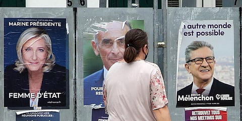 A woman walks past presidential campaign posters of French far-right presidential candidates Marine Le Pen and Eric Zemmour, and far-left leader Jean-Luc Melenchon, right, April 8, 2022.(Photo | AP)