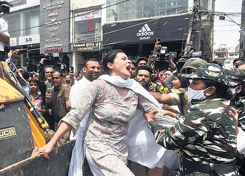 A woman is taken away by security personnel while trying to stop a bulldozer from rolling on during an anti-encroachment drive  of the South Delhi Municipal Corporation at Shaheen Bagh area on Monday.