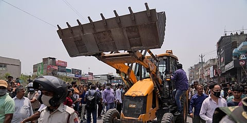 A bulldozer is retreated after officials stopped a demolition drive in New Delhi. (Photo | AP)