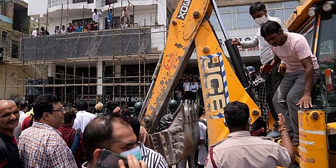 Residents and officials crowd around a bulldozer during a demolition drive in New Delhi. (Photo | AP)