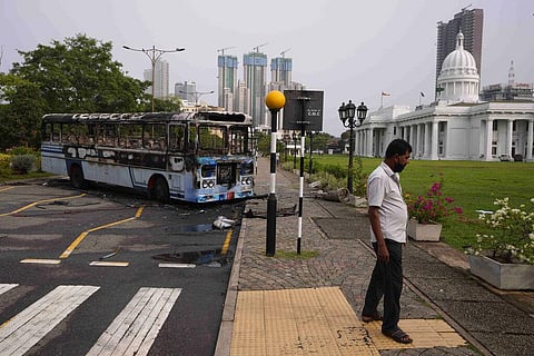 A Sri Lankan man walks on a pavement near a burnt bus a day after clashes between government supporters and anti-government protesters in Colombo. (Photo | AP)