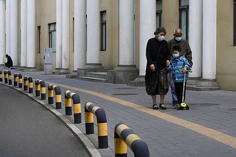 Residents wearing masks walk along a quiet street on Thursday, May 12, 2022, in Beijing.(Photo | AP)