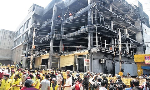 Security personnel and media at the site, as NDRF carries out rescue and relief work after a fire in Mundka. ( Photo | Parveen Negi, EPS)
