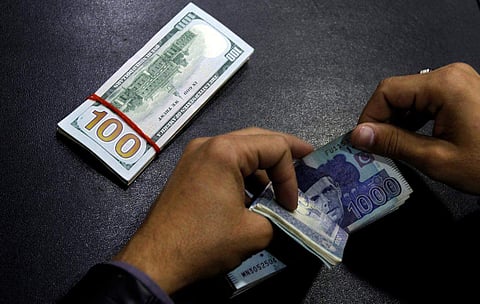 A currency trader counts Pakistani Rupee notes as he prepares an exchange of US dollars in Islamabad. (File photo| Reuters)