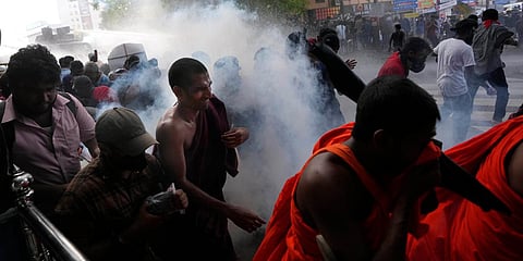Students run for cover as police fire tear gas to disperse protesting members of the Inter University Students Federation during an anti government protest in Colombo. (Photo| AP)