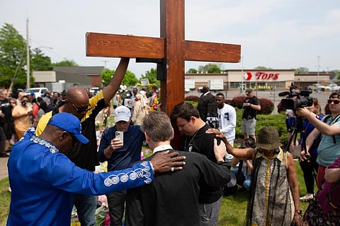 A group prays at the site of a memorial for the victims of the Buffalo supermarket shooting outside the Tops Friendly Market. ( Photo | AP)