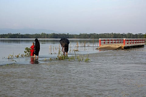 People make their way through a flooded road after heavy rains in Sylhet on May 23, 2022. (Photo | AFP)