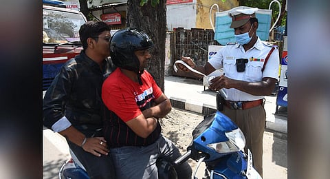 A traffic policeman slaps a fine on motorists at a traffic signal in Periyamet on Monday. (Photo | Ashwin Prasath, EPS)
