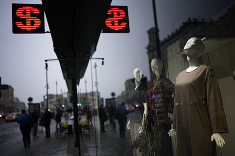People walk past a currency exchange office screen displaying the exchange rates of U.S. Dollar and Euro to Russian Rubles in Moscow's downtown, Russia. (Photo | AP)