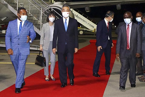 China's Foreign Minister Wang Yi, center, is escorted from his plane on his arrival in Honiara, Solomon Islands, early Thursday, May 26, 2022. (Photo | AP)