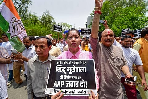 A Congress activist holds a placard during a protest over killing of Punjabi singer and Congress leader Sidhu Moose Wala, in New Delhi. (Photo | PTI)