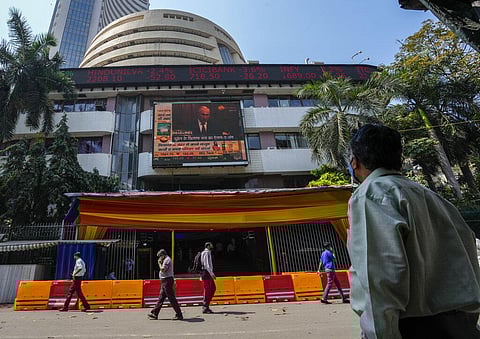 A man watches a screen showing Russian President Vladimir Putin on the facade of the Bombay Stock Exchange (BSE) building in Mumbai, India. (Photo | AP)